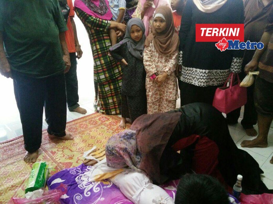 Hasida mengucup jenazah anaknya sebelum dikebumikan. FOTO 