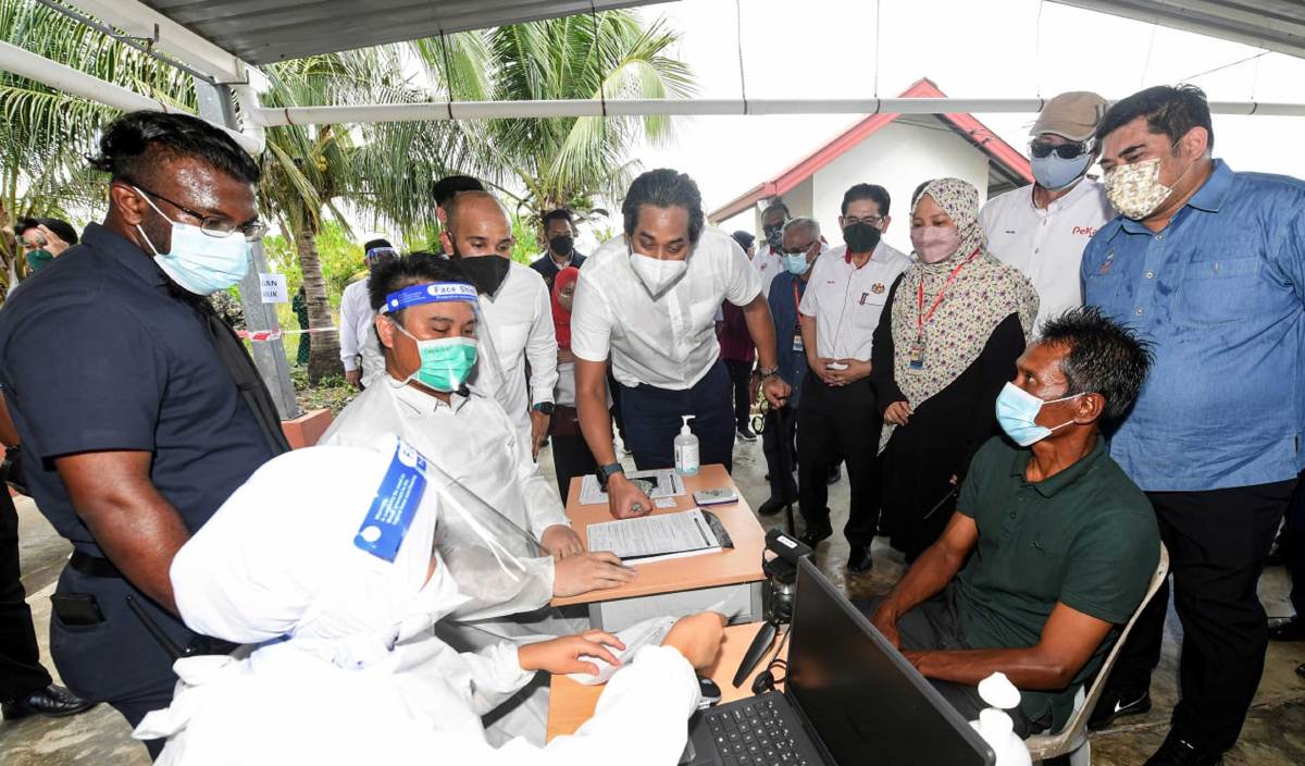 KHAIRY Jamaluddin (tengah) melihat proses pendaftaran penerimaan vaksin penduduk yang tidak mempunyai dokumen sewaktu melawat aktivi outreach pemberian vaksin kepada penduduk di Pulau Larapan. FOTO BERNAMA