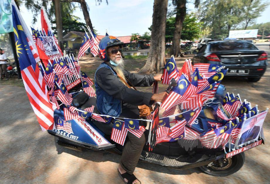 SEMANGAT patriotik yang ditunjukkan Jusop dengan menghiasi motosikalnya dengan 100 Jalur Gemilang ketika ditemui di Pantai Geting. FOTO NIK ABDULLAH NIK OMAR