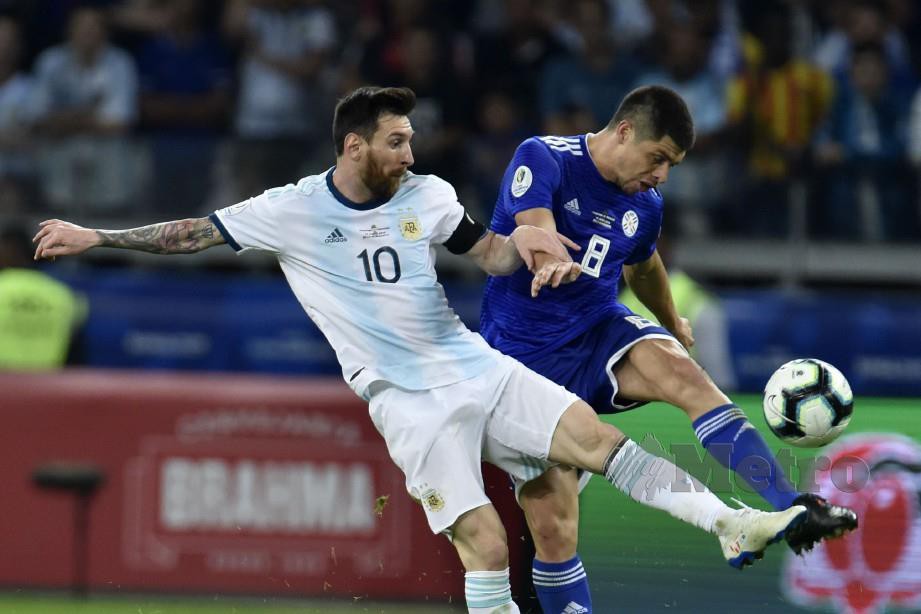 Messi (kiri) dicabar pemain Paraguay Rodrigo Rojas pada aksi Argentina menentang Paraguay dalam perlawanan kumpulan B Copa America. FOTO AFP