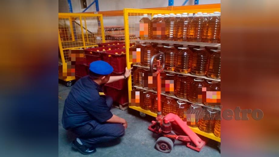 Anggota KPDNHEP memeriksa minyak masak sebelum merampas dan menyitanya dalam serbuan di sebuah syarikat pembungkusan minyak masak di Ipoh hari ini. Foto Ihsan KPDNHEP