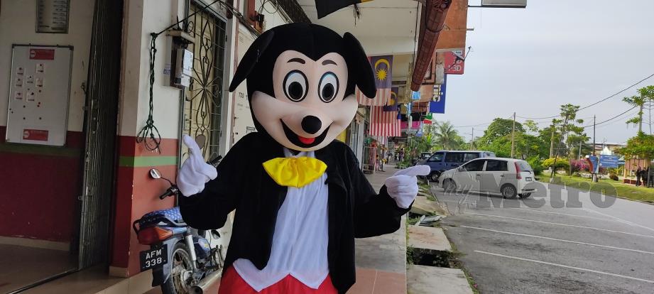RAJESWARY yang memakai kostum Mickey Mouse membuat penghantaran kepada penerima di Pekan Slim River. FOTO ROSMAN SHAMSUDIN.