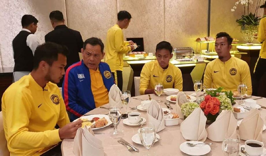 HAMIDIN (dua kiri) berkata sesuatu kepada penyerang negara Hadin Azman (kiri) ketika bersarapan dengan pemain di hotel penginapan, pagi tadi. — FOTO Persatuan Bolasepak Malaysia