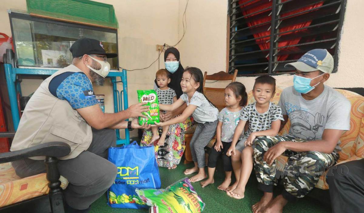 DR Asmadi (kiri) menyampaikan bantuan Milo kepada keluarga Mohd Khairul Hafiz selepas tular tiga anaknya memerlukan Milo dan susu. FOTO Mohd Rafi Mamat