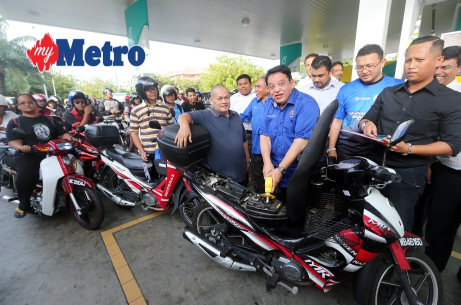 Tengku Adnan mengisi minyak motosikal secara percuma kepada pengguna kenderaan dua roda itu di Petronas Presint 9, Putrajaya. FOTO  Mohd Fadli Hamzah 