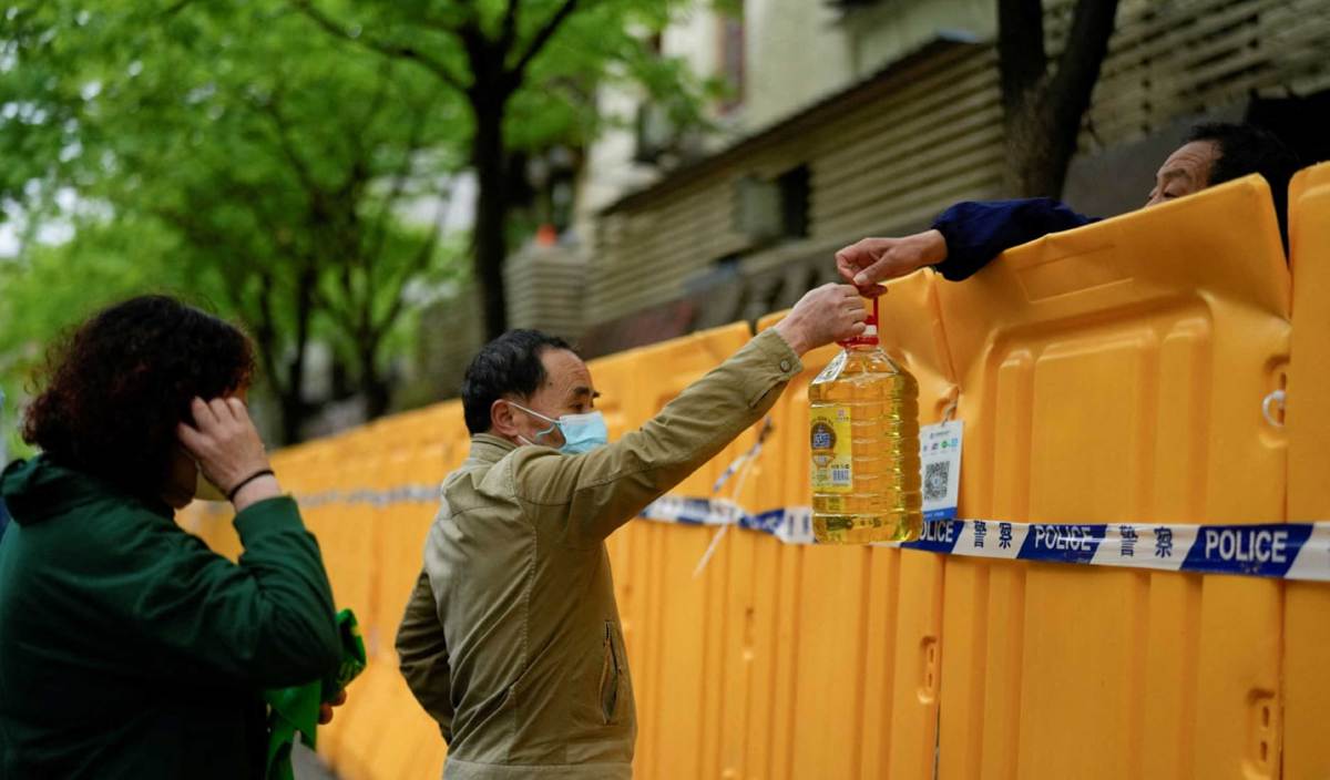 LELAKI menyerahkan minyak masak kepada seorang individu di sebuah pasar jalanan di Shanghai. FOTO Reuters