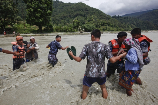 Anggota pasukan penyelamat Nepal membantu penduduk menyeberangi sungai semalam, selepas jambatan di Thulakhet, 200 kilometer di barat Kathmandu, runtuh. - Foto AP 