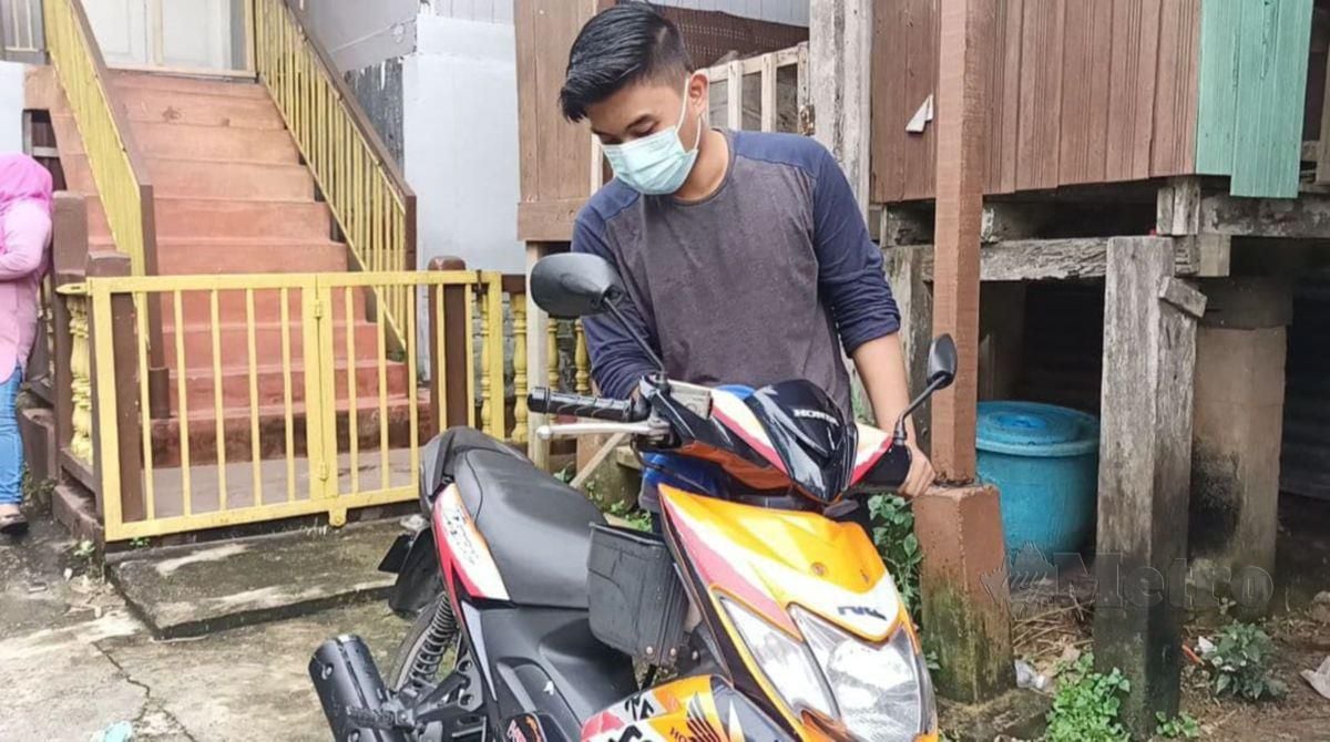 CHE MUHAMMAD Arif mengelap motosikal terpakai jenis Honda Dash 125 yang dibelinya minggu lalu ketika ditemui di rumahnya di Kampung Gok Kapur. FOTO SITI ROHANA IDRIS