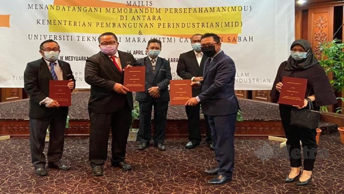 JOACHIM (tiga kiri) menyaksikan pertukaran MoU di antara wakil Kementerian Pembangunan Perindustrian Sabah dengan UiTM Sabah.  FOTO Ihsan Kementerian Pembangunan Perindustrian negeri.