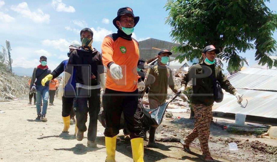 HIDAYAT dan Nik Abdul Aziz membantu mengeluarkan mayat dari kawasan bencana banjir lumpur dan gempa bumi di perkampungan Petobo. FOTO NSTP