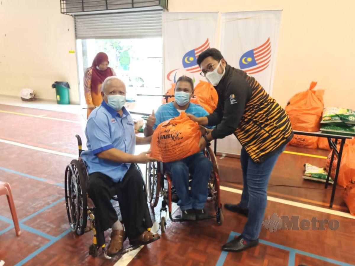 MEGAT (kanan) ketika menyampaikan sumbangan kepada atlet paralimpik Melaka di Dewan Komuniti Paya Rumput hari ini. FOTO Nazri Abu Bakar