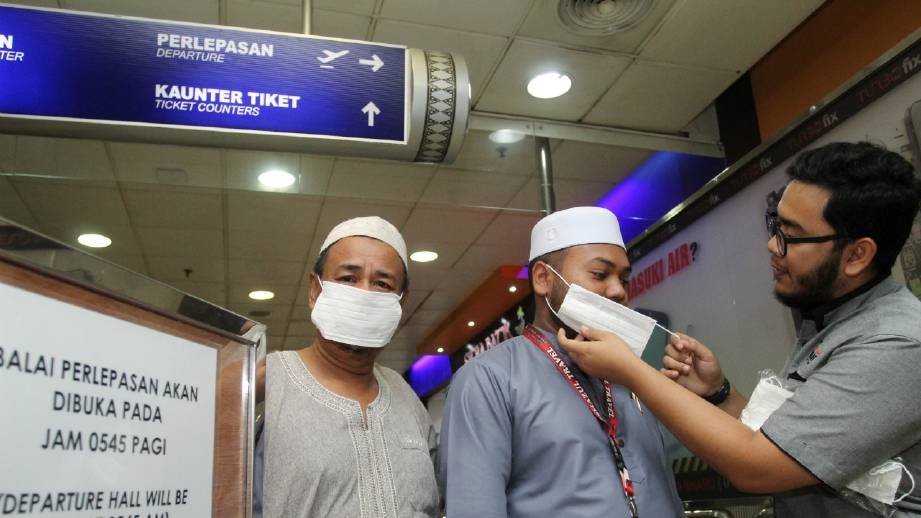 ABDUL Rahim (kanan) mengagihkan penutup hidung dan mulut. FOTO Nik Abdullah Nik Omar.