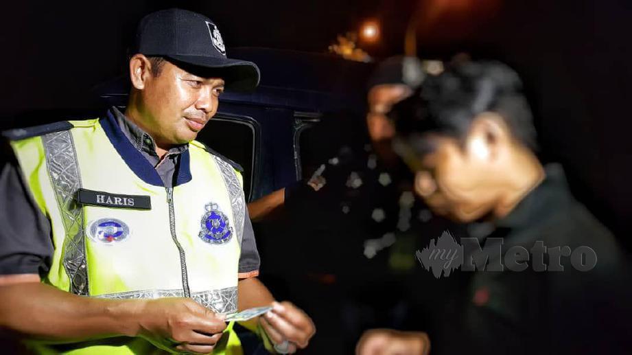 MOHD Haris memeriksa lesen seorang pengguna jalan raya yang ditahan kerana mabuk. FOTO Junaidi Ladjana 