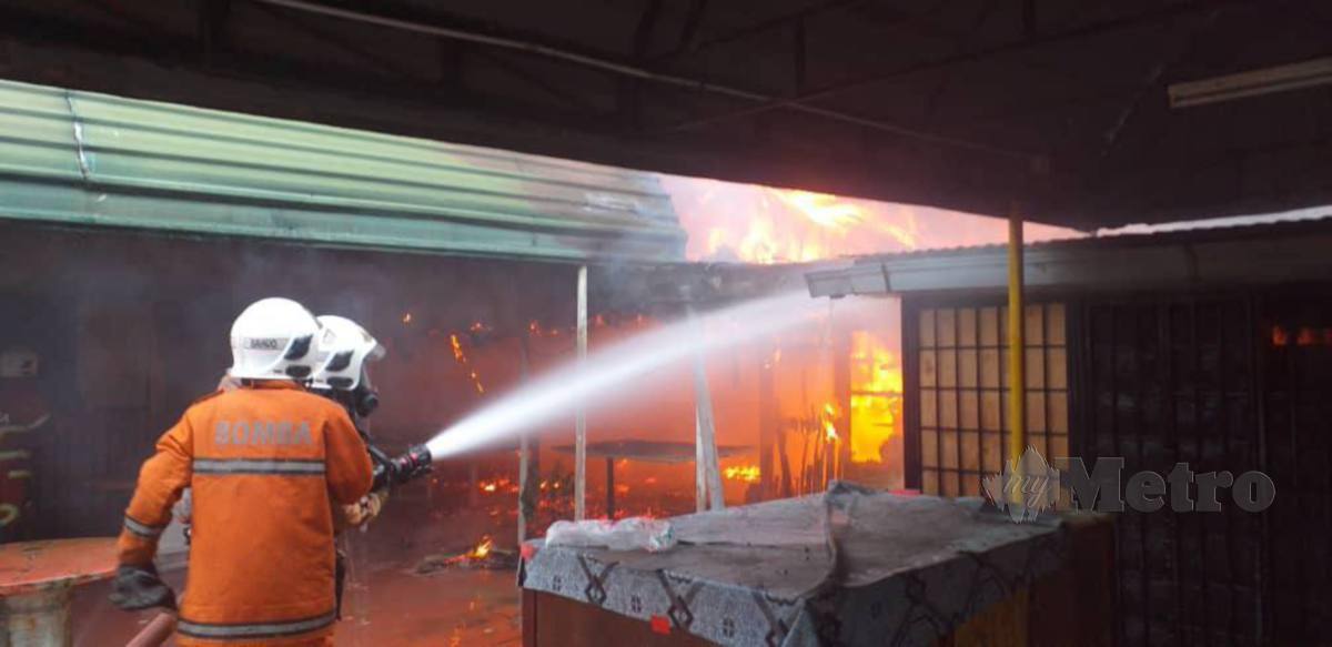 ANGGOTA bomba memadam kebakaran membabitkan dua unit kedai makan berhampiran Hospital Lama Kuala Krai. FOTO ihsan bomba