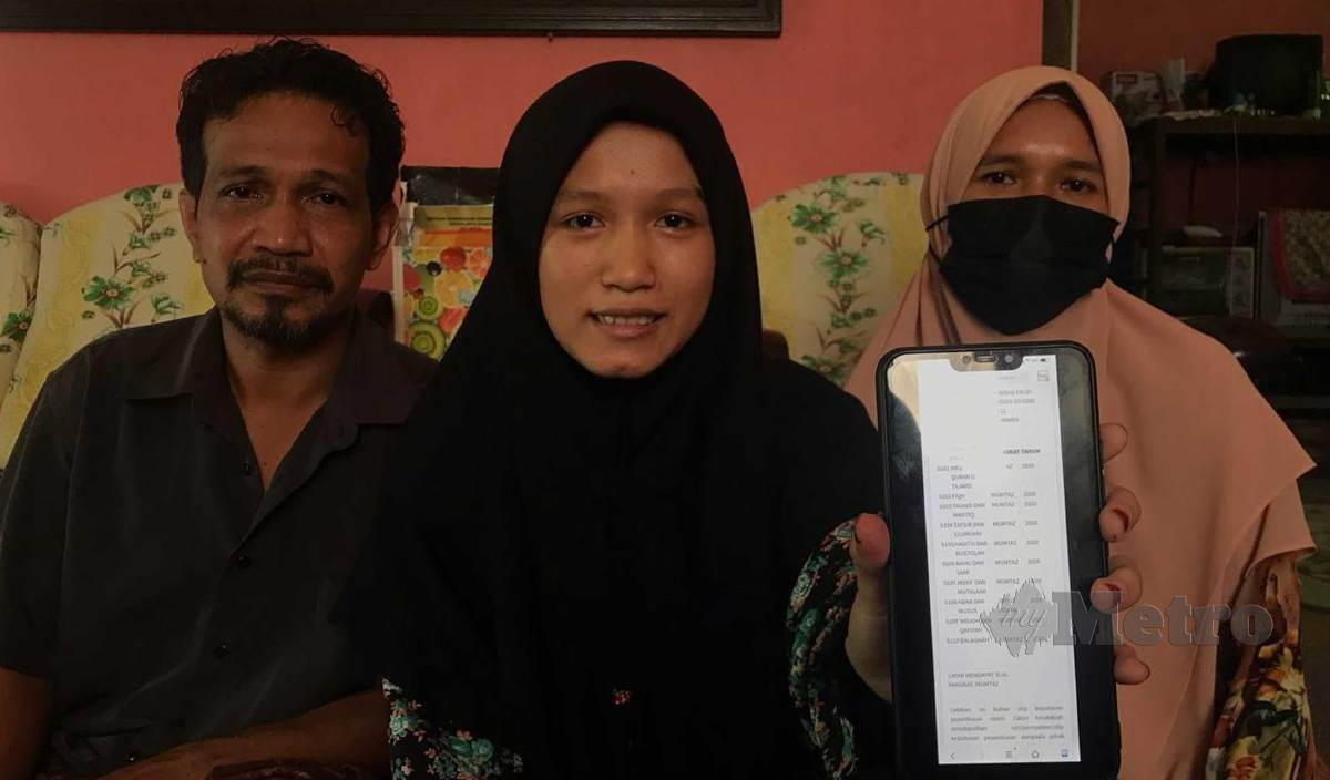 SITI Awanis (tengah) menunjukkan keputusan STAM kepada ibu bapanya ketika ditemui di rumahnya di Kampung Wakaf Stan. FOTO Hazira Ahmad Zaidi