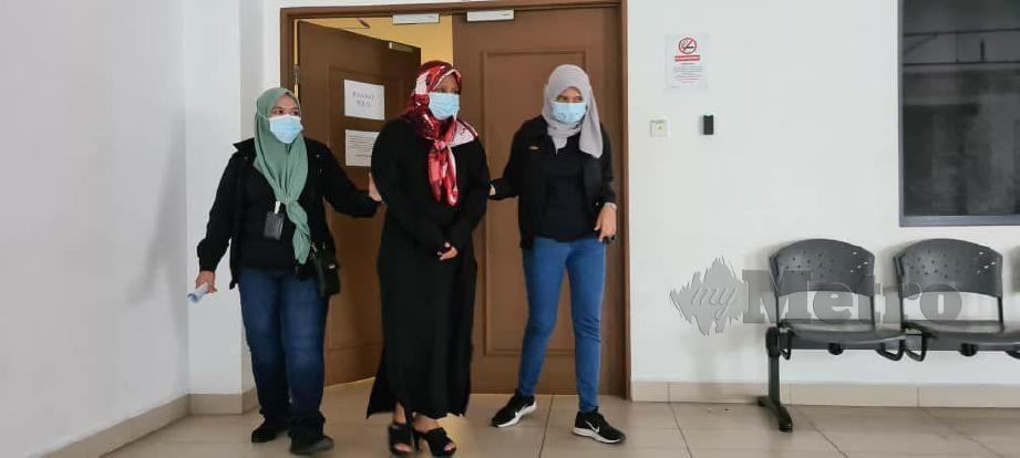 TERTUDUH (tudung merah) diiringi dua pegawai Bahagian Siasatan dan Penguatkuasaan JPN Sabah di Mahkamah Majistret Kota Kinabalu selepas didapati bersalah menggunakan MyKad palsu. FOTO Juwan Riduan
