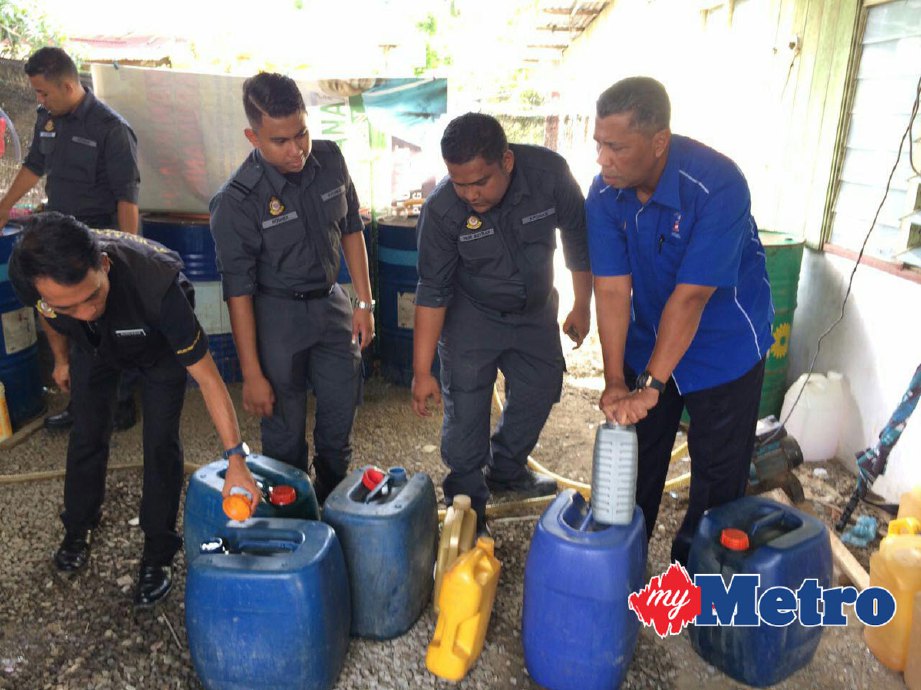 Jamal (kanan) meneliti petrol dan diesel yang disimpan di dua rumah sambil disaksikan oleh anggota penguat kuasanya. FOTO Aizat Sharif