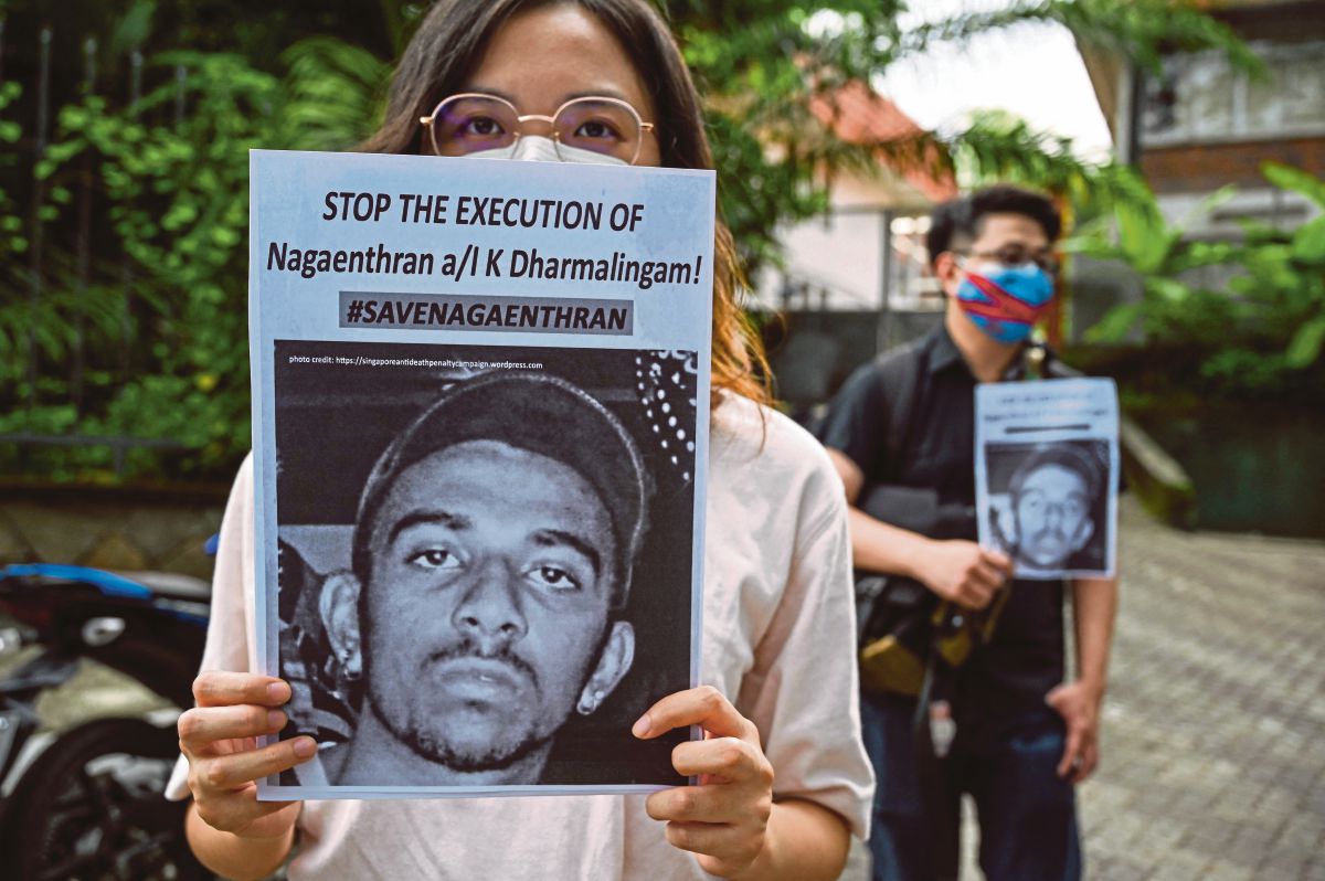 FOTO fail menunjukkan aktivis memegang plakad sebelum menghantar memorandum ke Parlimen Singapura membantah pelaksanaan hukuman mati ke atas Nagaenthran. FOTO AFP 
