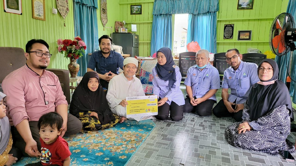 NORA (tengah) menyerahkan replika cek Faedah Pengurusan Jenazah kepada Mohd Nadzir ketika lawatan di rumah mereka Kampung Bendang Surau, Morak, di sini. FOTO Ihsan PERKESO