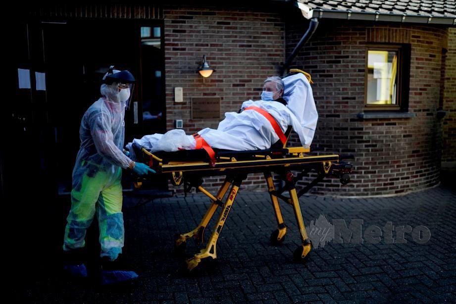 SEORANG kakitangan perubatan Belgium menolak seorang pesakit Covid-19 ke dalam sebuah ambulans di Liege, semalam. FOTO AFP