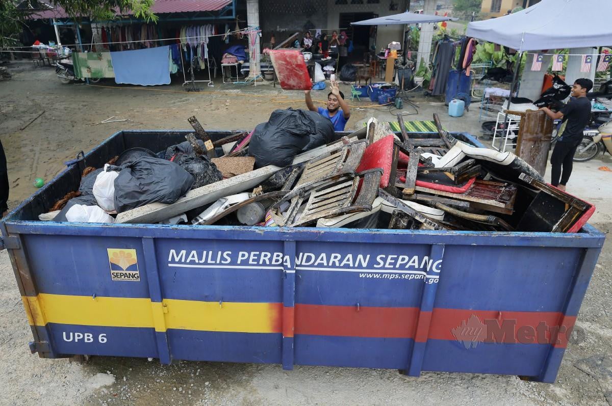 MANGSA banjir membuang perabot dan barangan yang tidak boleh digunakan selepas rumah mereka di Kampung Ginching, Sepang dilanda banjir. FOTO Mohd Fadli Hamzah.