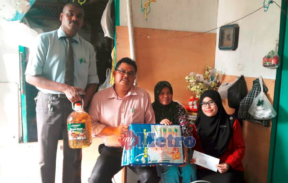 MAS Imran (dua dari kiri) menyampaikan sumbangan barangan keperluan kepada Serilah (dua dari kanan) di rumahnya di Kampung Melayu, Johor Bahru, hari ini. FOTO Mary Victoria Dass. 