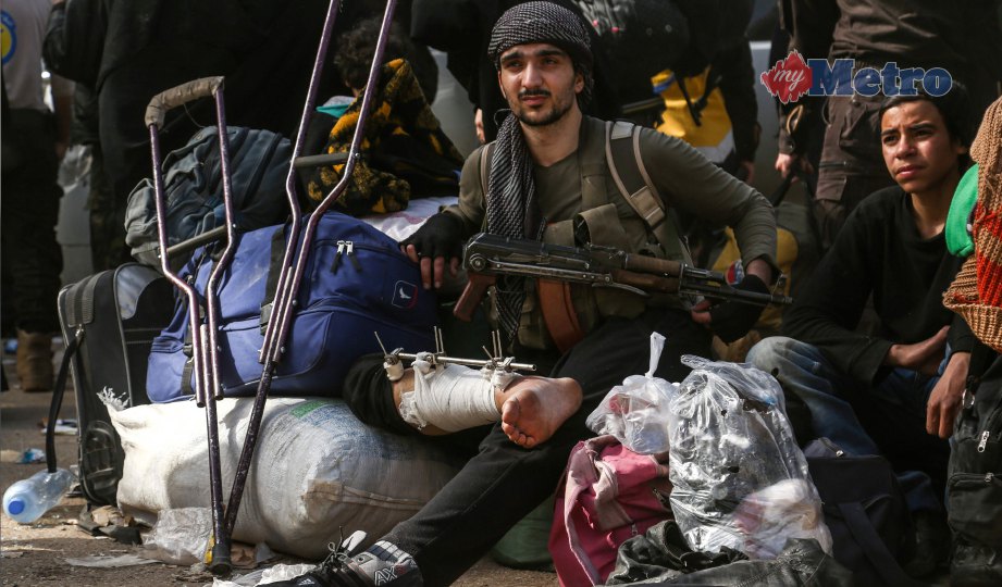 PEJUANG pemberontak Syria duduk dengan kaki dibalut dan bertongkat setibanya di Kampung Qalaat al-Madiq. FOTO AFP