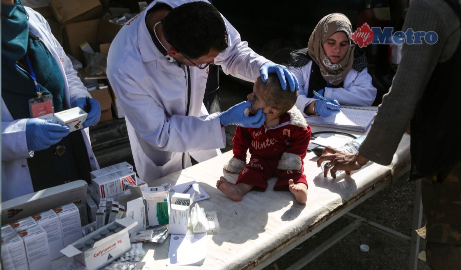 SEORANG doktor memeriksa kesihatan anak Syria yang dipindahkan dari Timur Ghouta  sebaik tiba di Kampung Qalaat al-Madiq. FOTO AFP