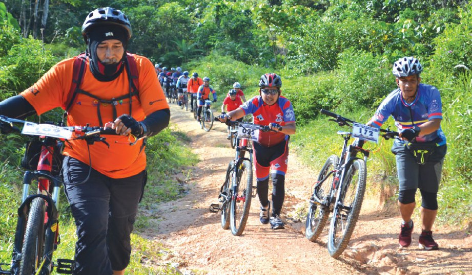 GELAGAT peserta yang menolak basikal ketika melalui kawasan bukit.