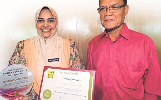 ADNAN menyampaikan  tajaan Yayasan Pahang kepada  Noorjahan di kompleks Yayasan Pahang Tanjung Lumpur, semalam.   