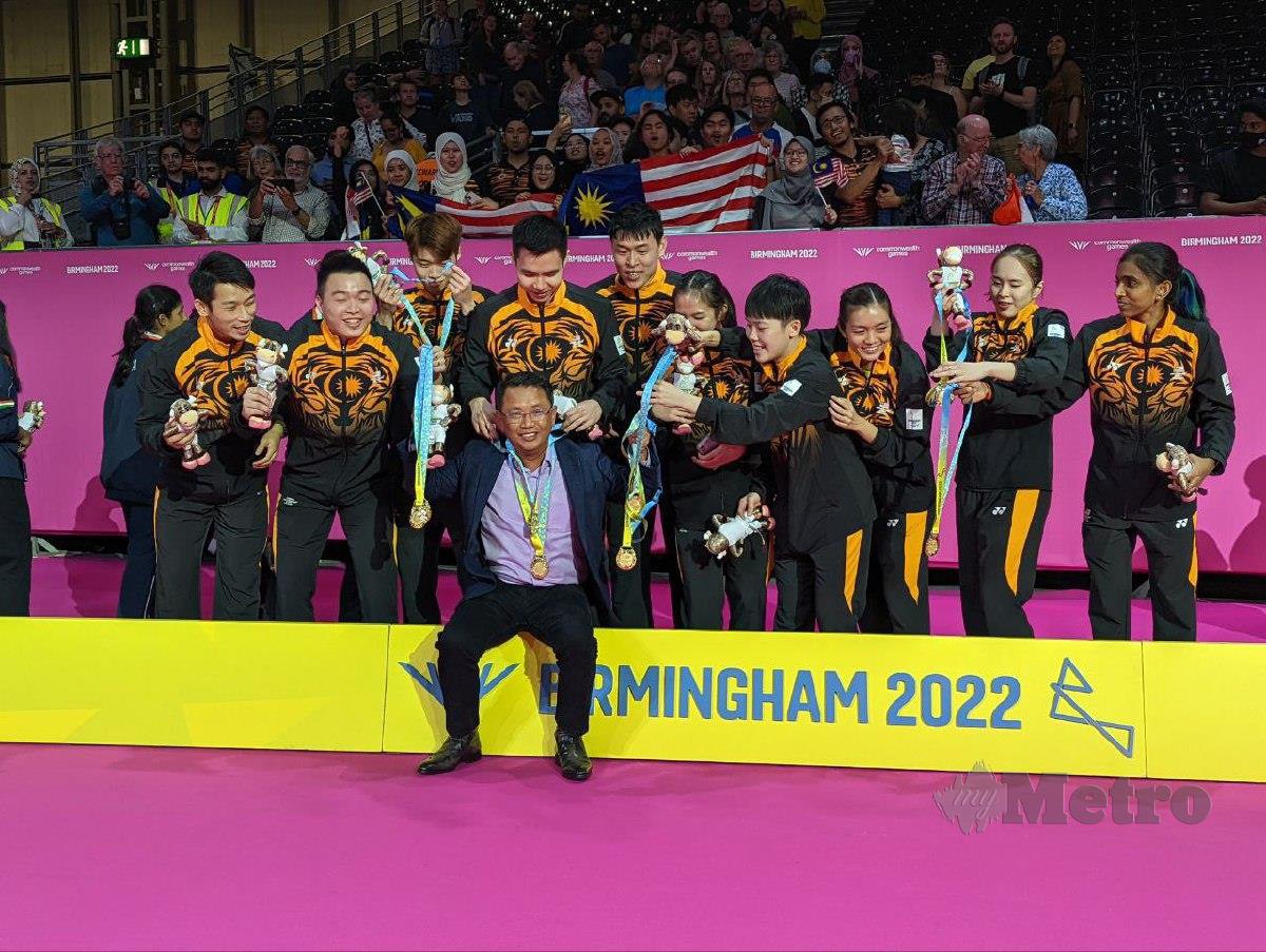 PEMAIN badminton negara memakaikan pingat emas kepada Norza (duduk depan) selepas memenangi acara berpasukan campuran, malam tadi. FOTO MAJLIS OLIMPIK MALAYSIA