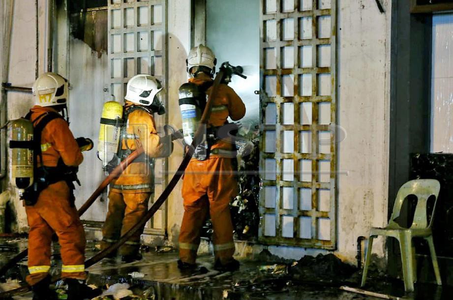 ANGGOTA bomba berusaha memadamkan kebakaran kedai runcit di Lido. FOTO Edmund Samunting