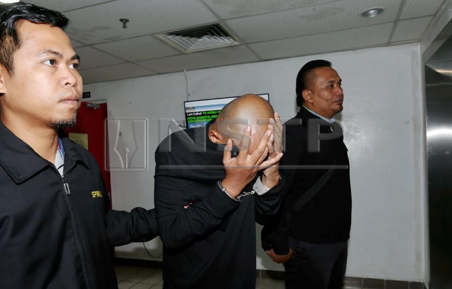 TERTUDUH, Suhaimee Wan Mohamad diiringi pegawai SPRM di Mahkamah Sesyen Kuala Terengganu. FOTO Imran Makhzan