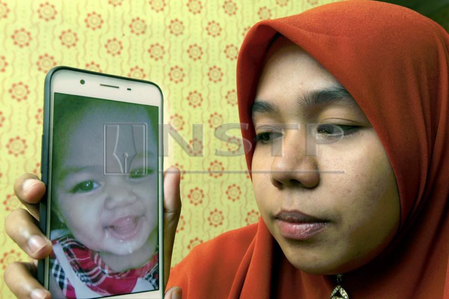 NORAIHAN menunjukkan gambar anaknya, Nur Muazara Ulfa yang meninggal dunia dipercayai didera. FOTO Syamsi Suhaimi