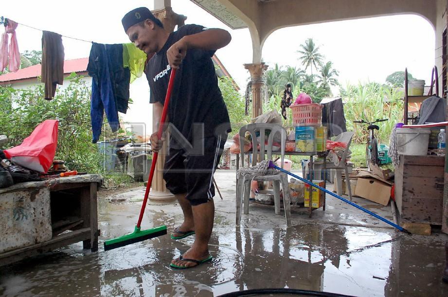 SUKARELAWAN membantu membersihkan rumah mangsa banjir di Jalan Kolam Air, berhampiran Taman Seri Bayu, Alor Gajah. FOTO Hassan Omar