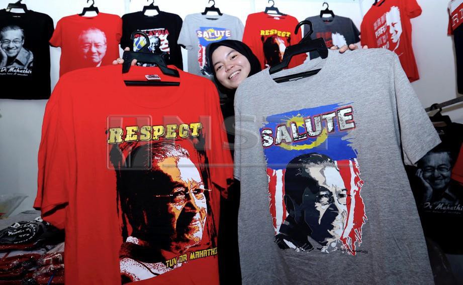 PENIAGA, Zatul Athirah Zulkipli ketika menunjukkan baju yang dicetak berwajah Tun Dr Mahathir Mohamad ketika tinjauan di gerai jualan pada Perhimpunan Agung Tahunan Parti Pribumi Bersatu Malaysia kali yang kedua 2018. FOTO Ahmad Irham Mohd Noor