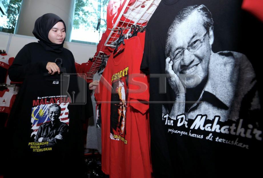 PENIAGA, Zatul Athirah Zulkipli menyusun baju yang dicetak berwajah Tun Dr Mahathir Mohamad ketika tinjauan di gerai jualan pada Perhimpunan Agung Tahunan Parti Pribumi Bersatu Malaysia. FOTO Ahmad Irham Mohd Noor