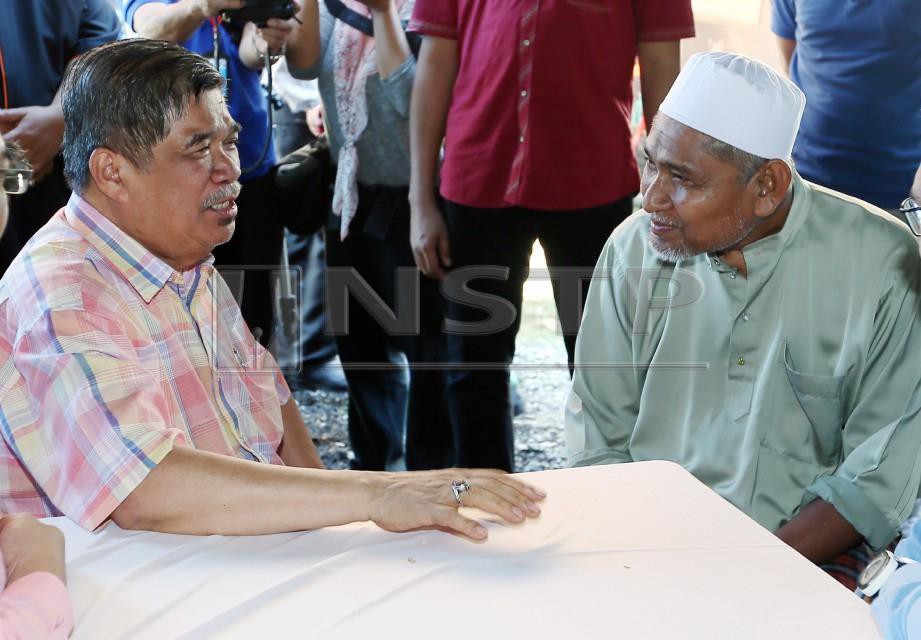 MOHAMAD Sabu berbual dengan ayah Allahyarham Muhammad Adib, Mohd Kassim Abdul Hamid ketika melawat keluarga Allahyarham di Kampung Tebengau, Kuala Kedah. FOTO Amran Hamid