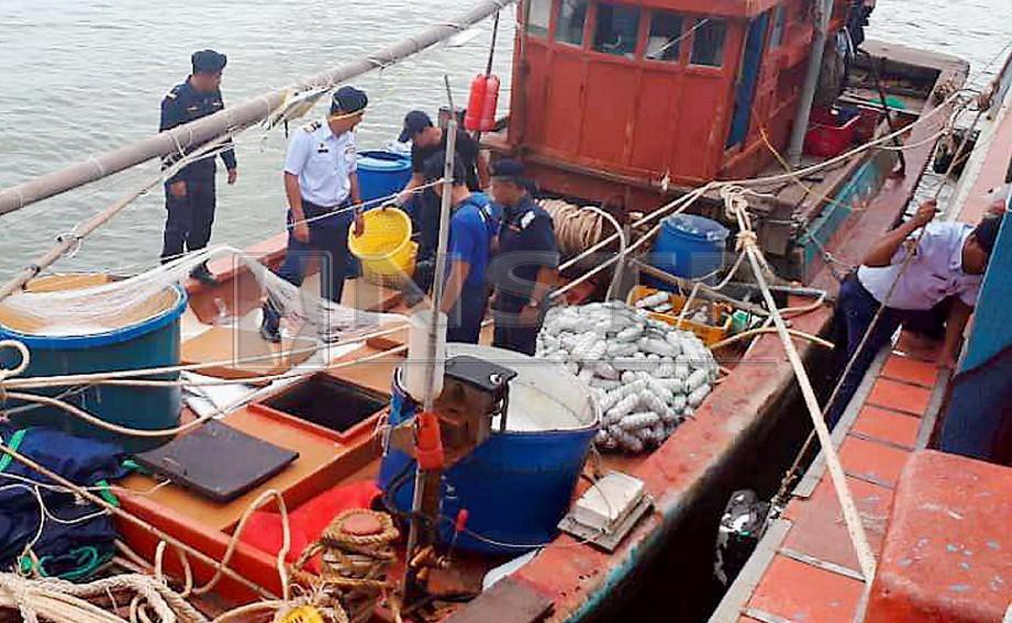 Penguat kuasa memeriksa bot nelayan asing selepas dibawa ke jeti APMM Kemaman. FOTO Rosli Ilham