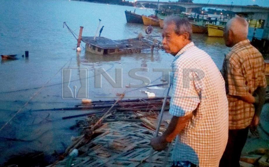 Wan Mahmud (bertongkat) melihat botnya yang tenggelam. FOTO Rosli Ilham