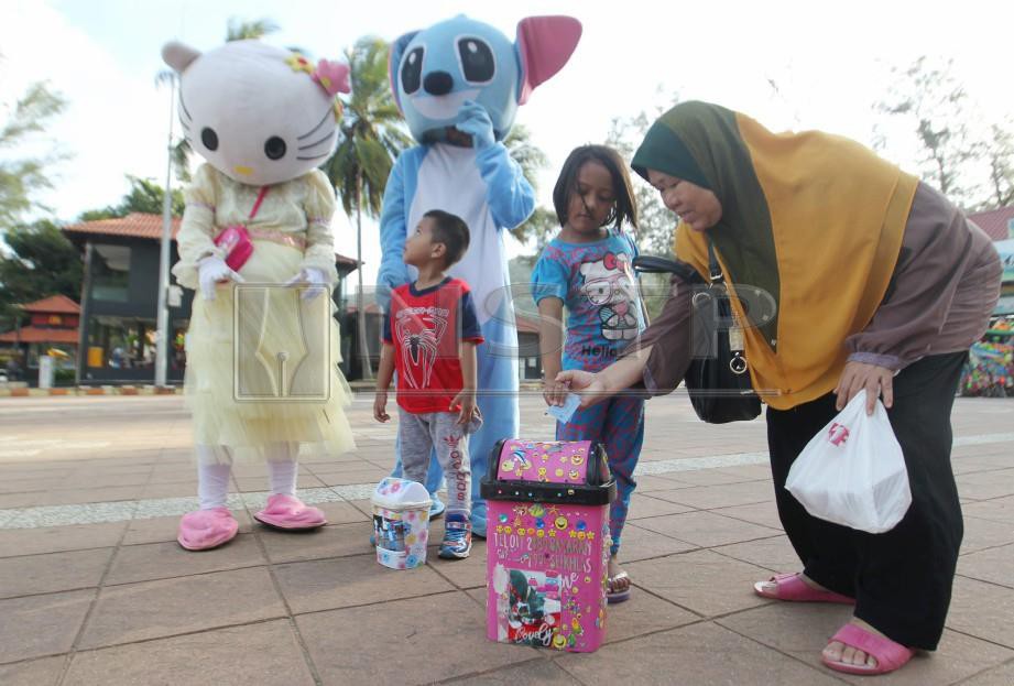 Siti Endon menghiburkan orang ramai dengan maskot Hello Kitty di Teluk Cempedak. FOTO Farizul Hafiz Awang