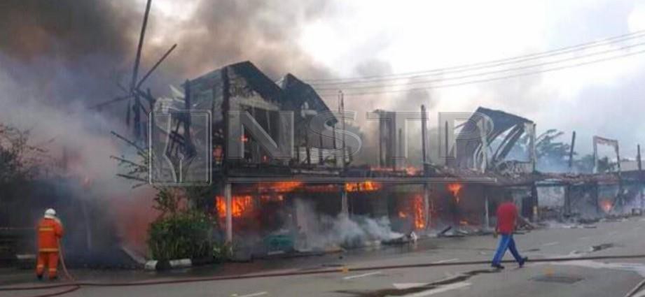 Anggota bomba memadam kebakaran lapan deretan kedai di pekan Spaoh, Betong. FOTO Ihsan bomba
