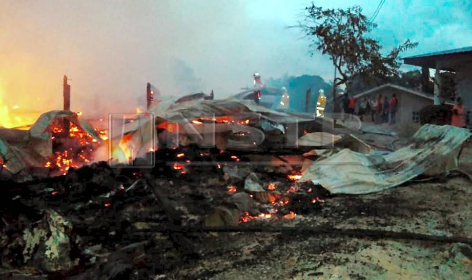 ANGGOTA bomba berusaha memadamkan kebakaran yang memusnahkan rumah panjang di Kampung Hobut Mantunggung. FOTO ihsan bomba