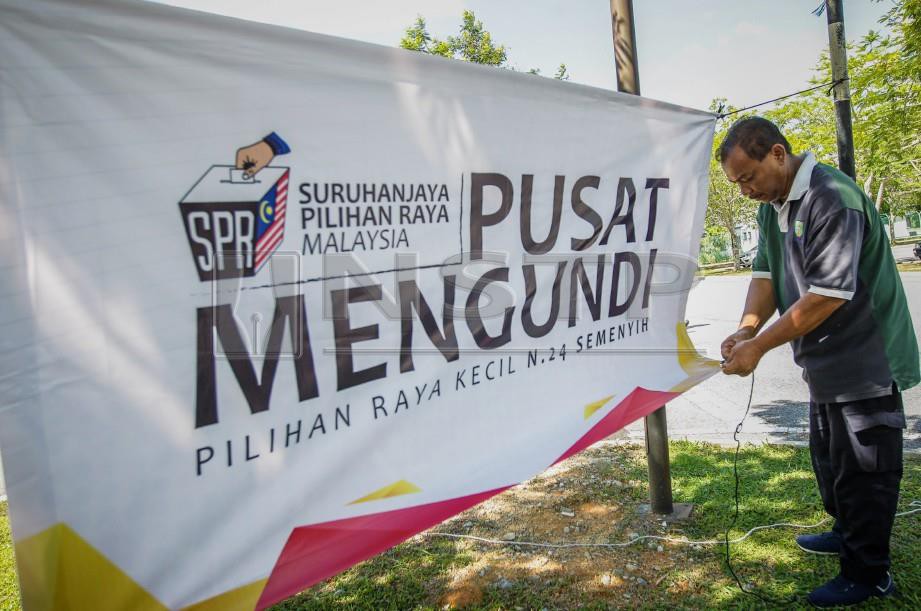 PETUGAS SPR, Jamaluddin Ishak menggantung kain rentang ketika membuat persiapan terakhir hari mengundi awal di Kem Batalion 4 Pasukan Gerakan Am (PGA), Semenyih. FOTO Asyraf Hamzah