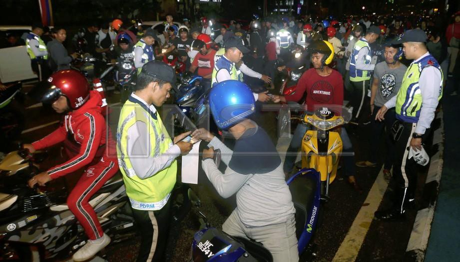 ANGGOTA polis mengeluarkan saman kepada penunggang motosikal dalam operasi bersepadu di Jalan Raja Laut, Kuala Lumpur. FOTO Rosdan Wahid