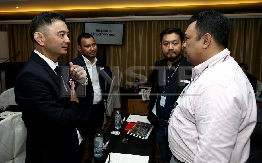 ROCHE (kiri) memberi penerangan kepada pelanggan ketika ekspo NewsConnect di Hotel Majestic Kuala Lumpur. FOTO Eizairi Shamsudin