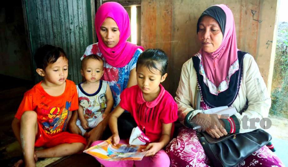 NADIN Junianti (kiri) bersama tiga anak melihat gambar suaminya, Jari Abdullah yang hilang sejak Disember lalu dipercayai diculik. FOTO Arkib NSTP