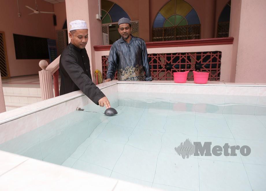 Ketua Imam Masjid Al-Ikhlasiah Pantai Dalam, Talhah Ab Aziz, 38, (kiri) melihat bekalan air yang penuh dalam kolah masjid ketika tinjauan air di sekitar Kuala Lumpur semalam. FOTO Zulfadhli Zulkifli