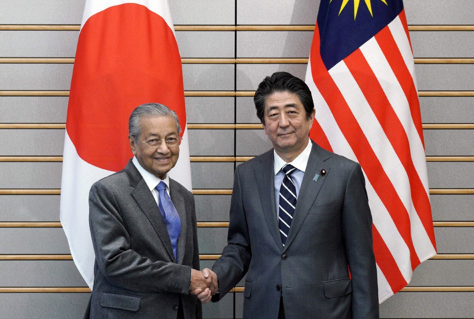 DR Mahathir berjabat tangan dengan Abe. FOTO Bernama