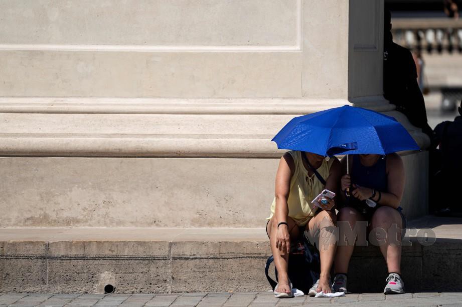 PENGUNJUNG berhampiran Louvre, Paris ketika gelombang panas luar biasa . FOTO AFP